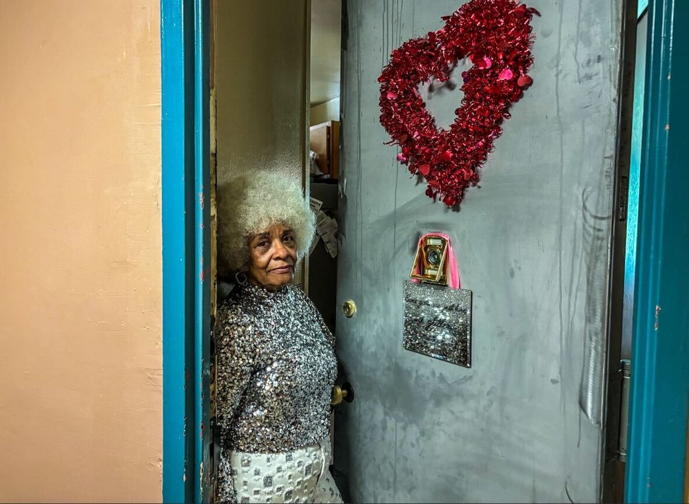 Maria Santos stands in the doorway of her apartment in the Chelsea Addition.