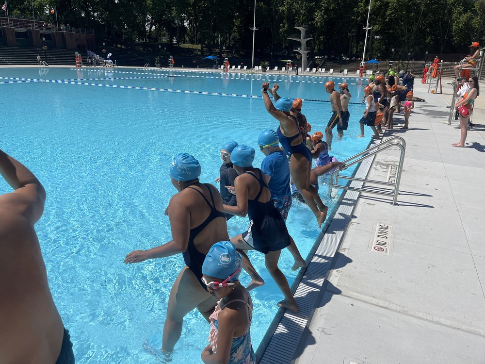 People jump into a pool.