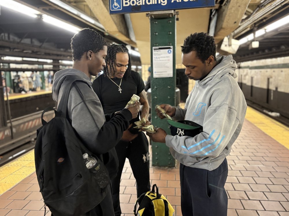 Three men collecting cash on a subway platform.