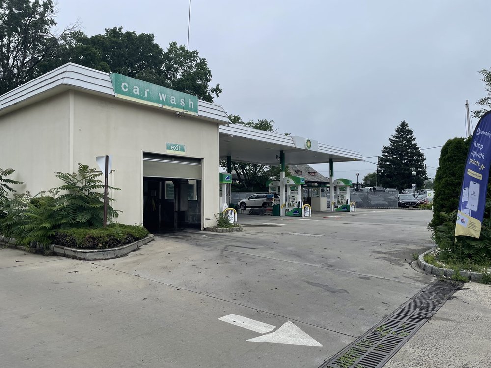 A gas station in Westfield New JErsey, with a sign reading "car wash" at the nearest building"