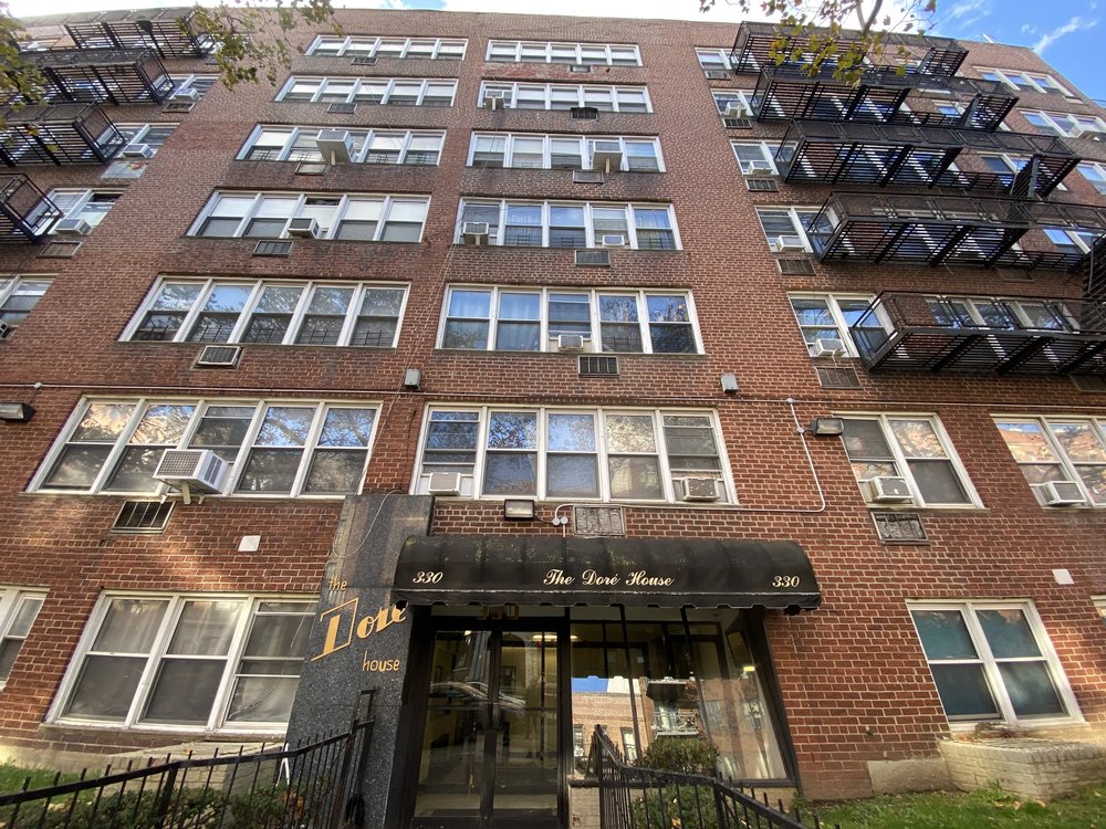 The exterior of a residential building in Flatbush, a brick complex with black iron fire escapes.