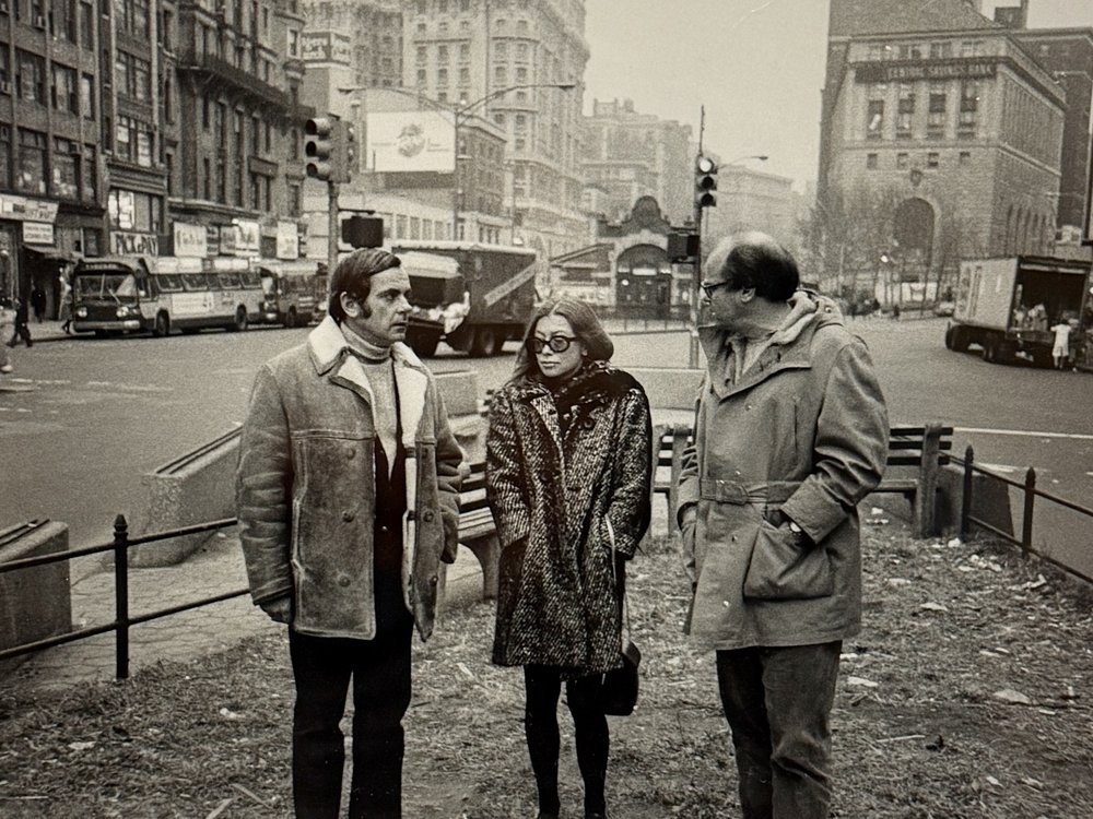 A photograph of a woman standing beside two men.