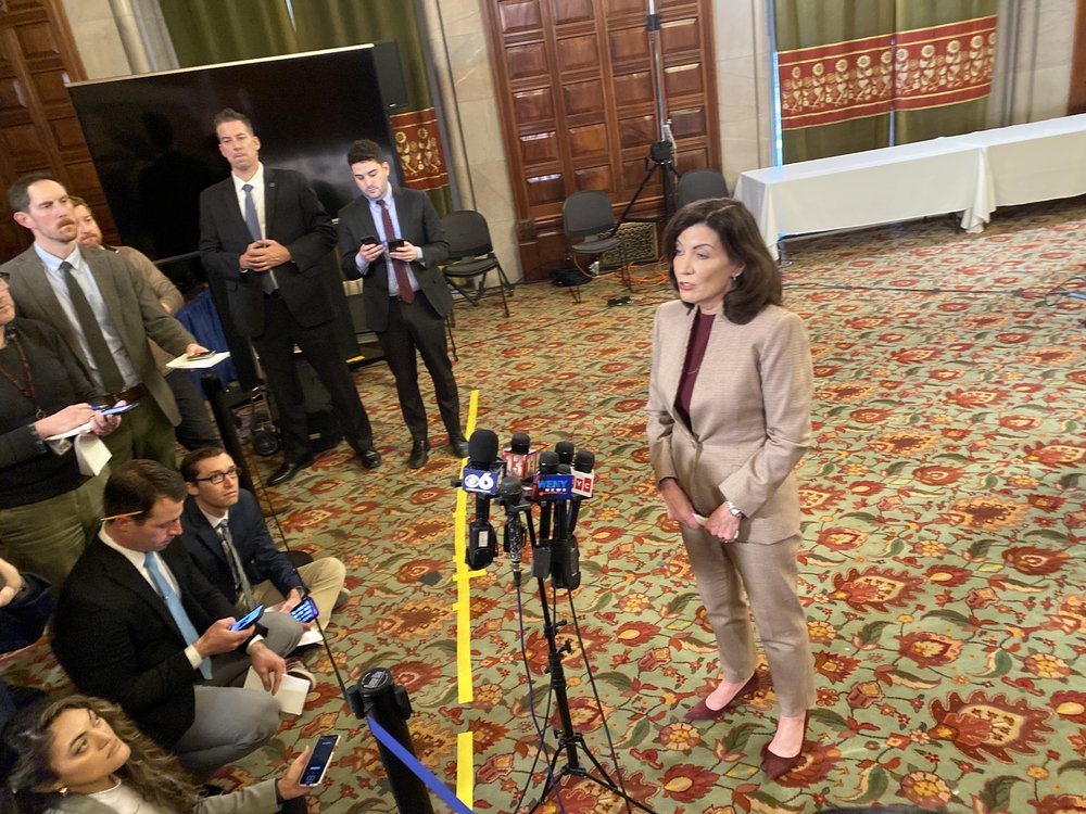 Hochul speaks a press conference with an aide to the side.