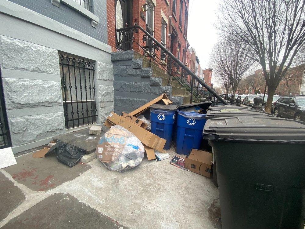 Loose trash in front of a Brooklyn townhouse.
