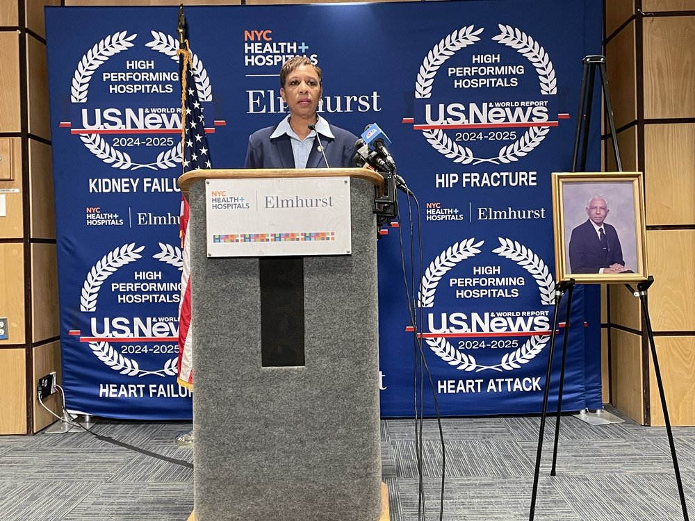 Adrienne Adams at a podium, near a framed photo.