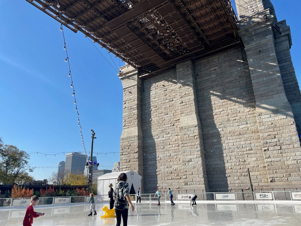 An ice skating rink under the Brooklyn Bridge.