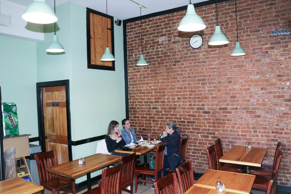 The interior of a small restaurant with brick walls.