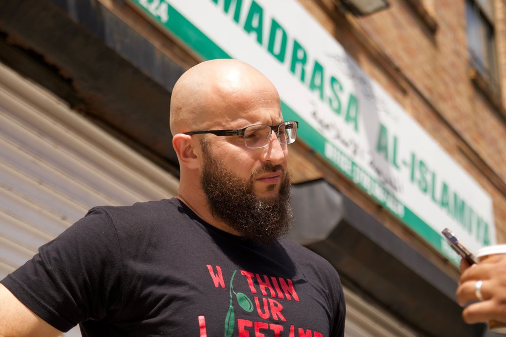 Mohamed Bahe, with a serious expression,speaks to someone off camera