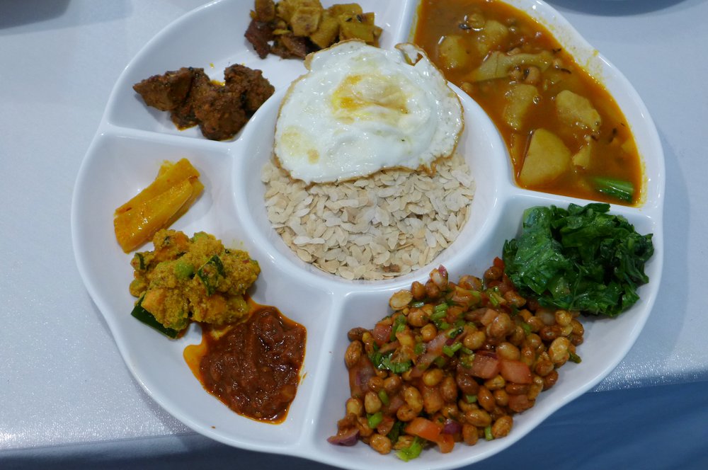 A plate with rice in the middle and assorted foods arranged in a circle around it.