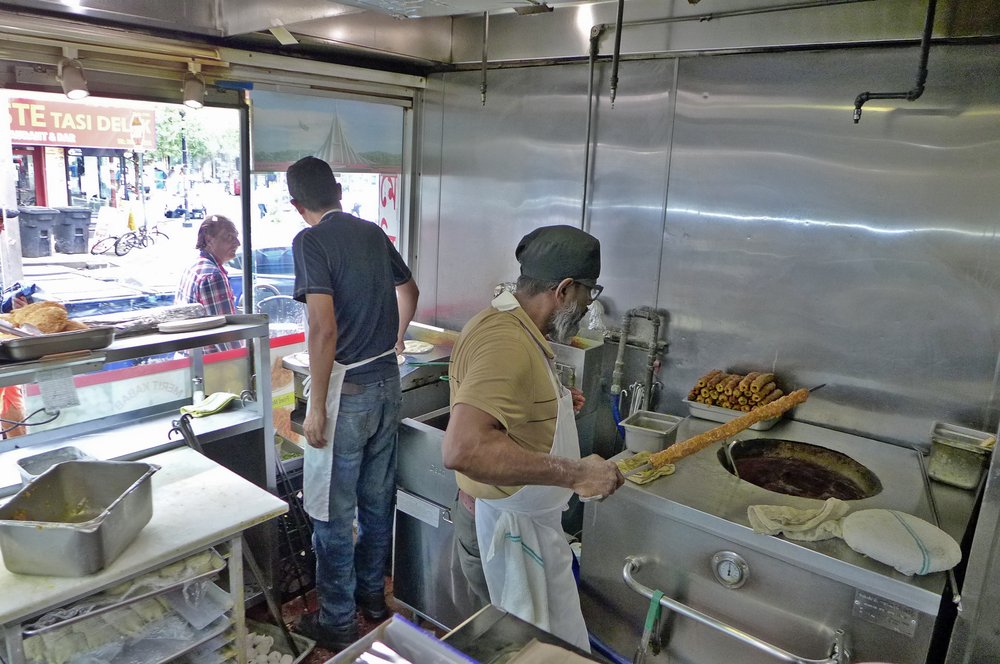 Two people working inside a kitchen.