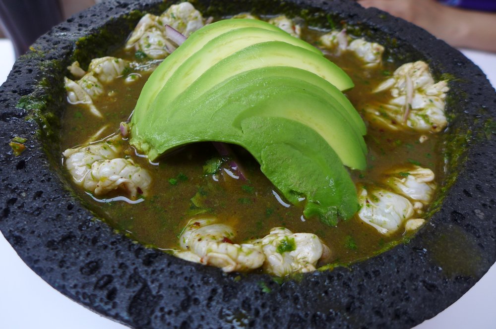 A brown soup with avocado slices on top.