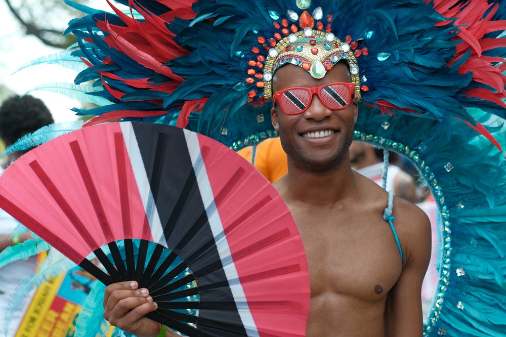 A man holding a fan with the Trinidadian flag on it.