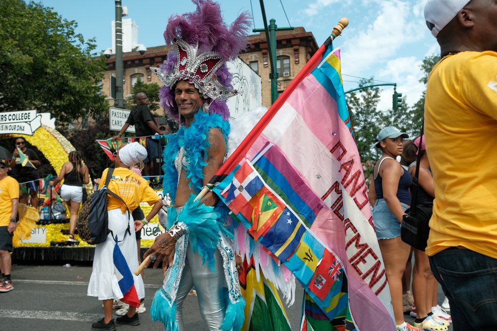A person in a colorful costume with a trans flag.