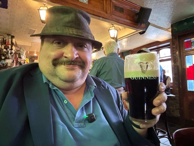 A man holds a beer in a glass.