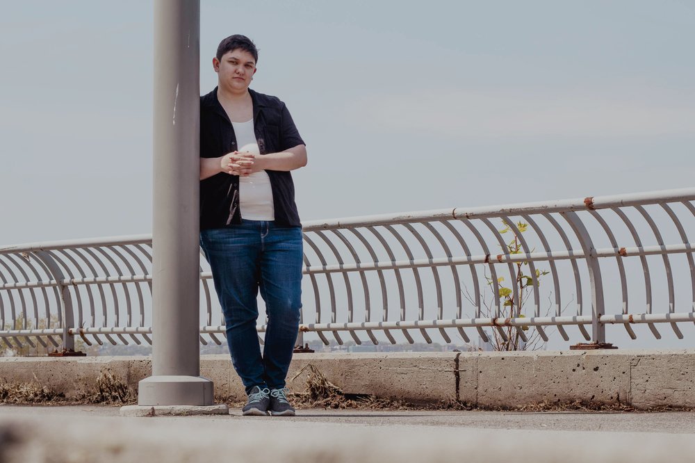 A person poses by a fence