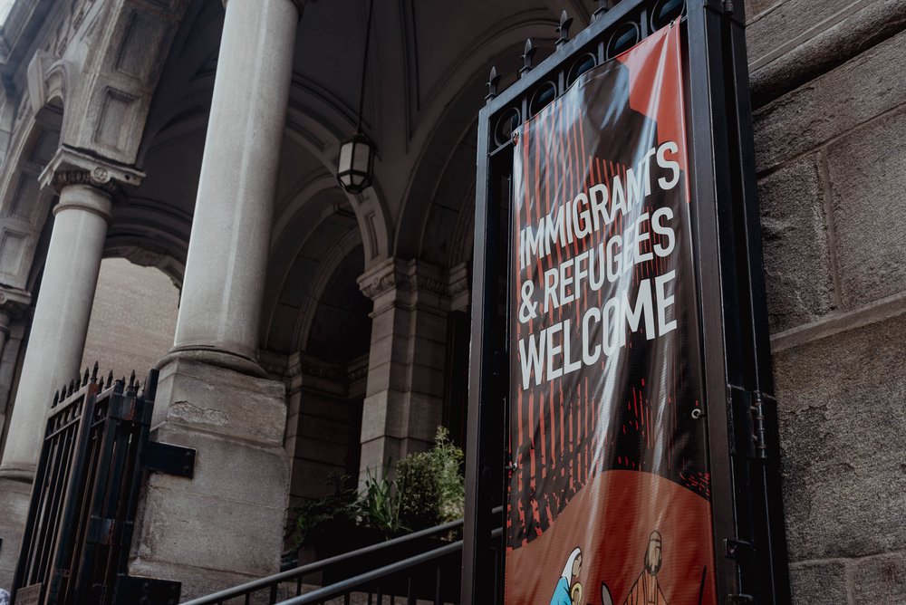 A banner that welcome immigrants and refugees hangs from a church wall.