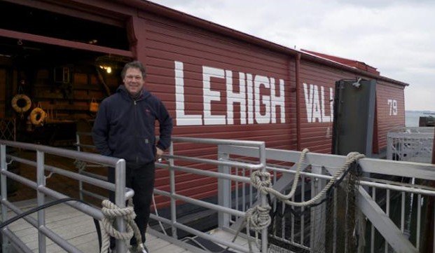 A man stands in front of a red barge.