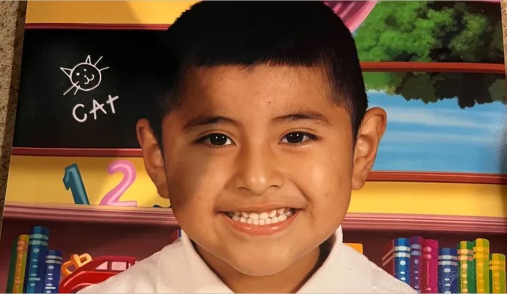 A young boy smiling in a classroom.