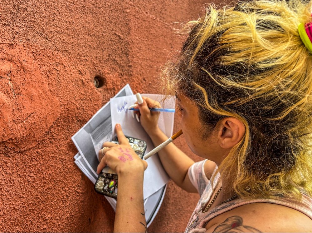A woman writes her signature on a piece of paper.