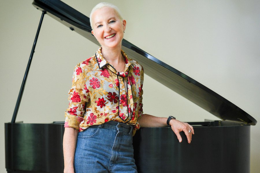 A woman standing in front of a piano.