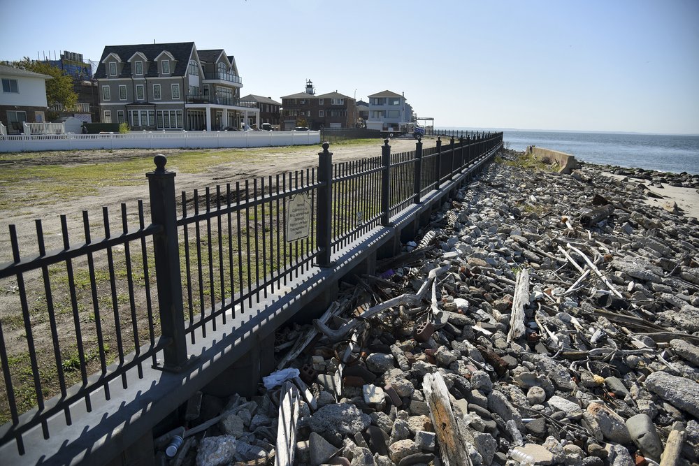 Rocks, and branches stand between a metal fence, and the Atlantic Ocean. About 25 yards behind the fence are the rebuilt, glistening beachfront mansions of the Seagate neighborhood in Brooklyn.
