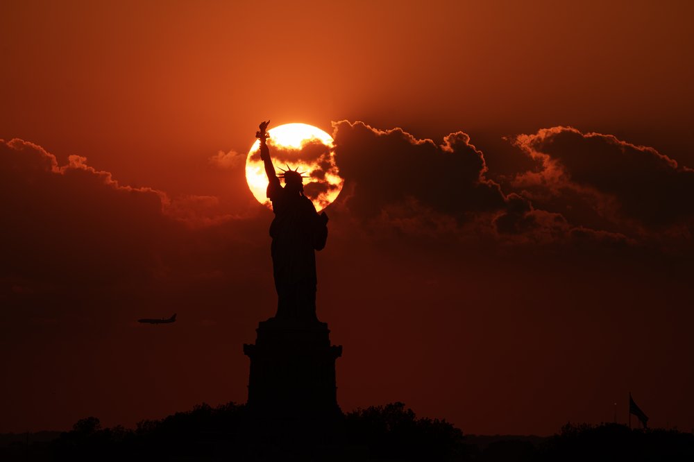 A photo of a sunset behind the Statue of Liberty.