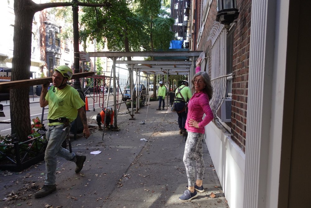 a woman stands on a New York City sidewalk