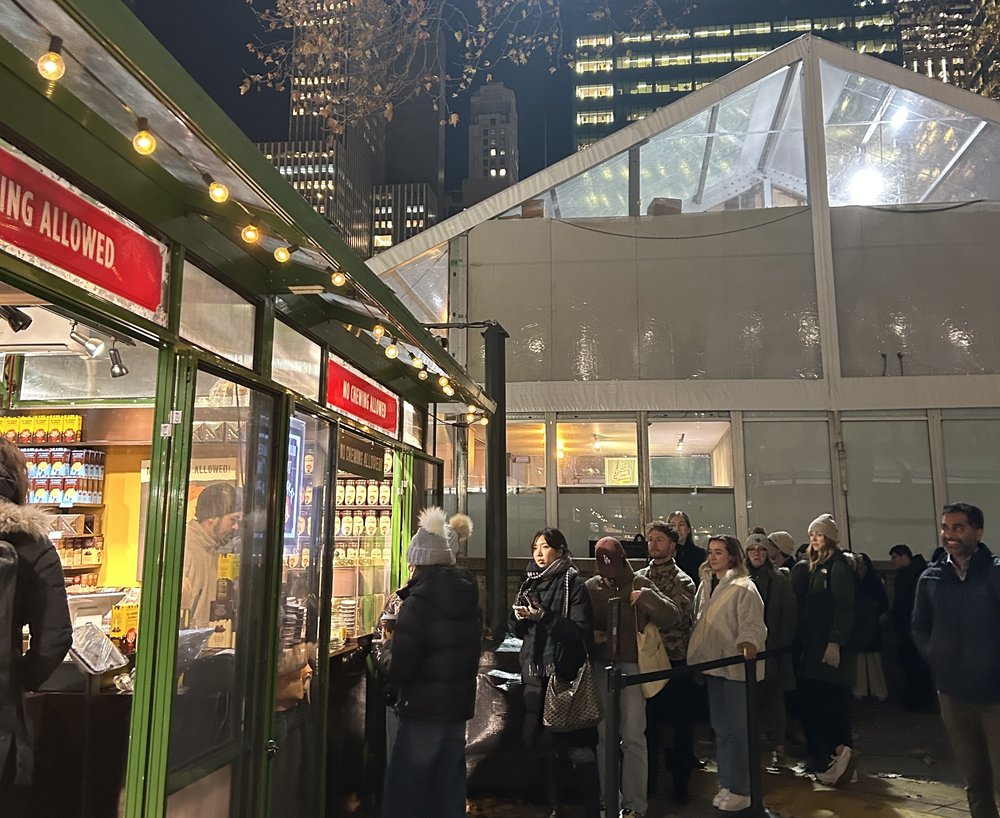 A line snakes out of a food stand and into the rain.