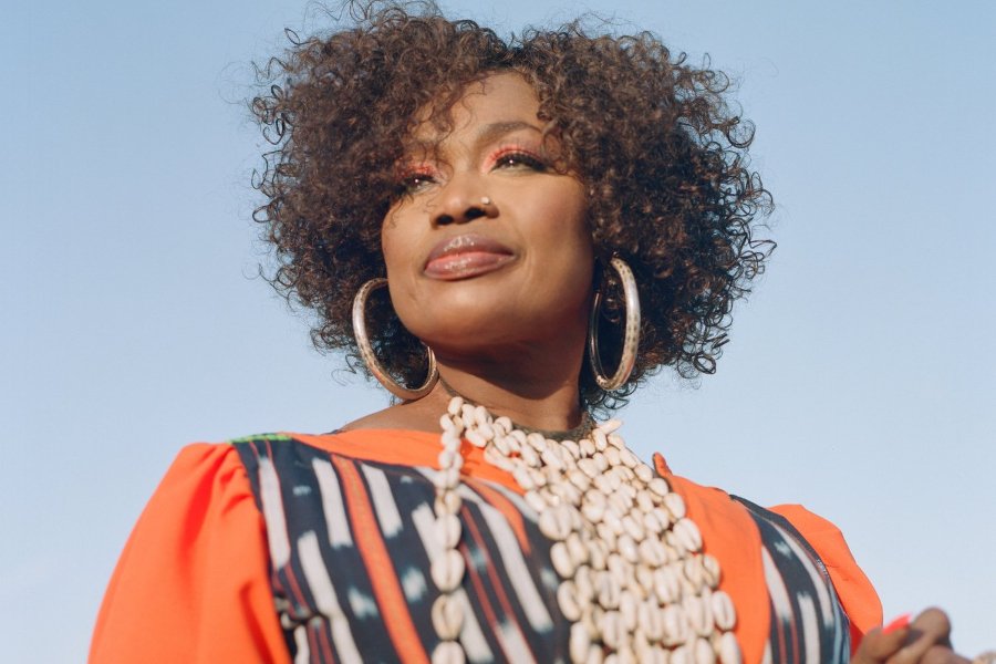 A woman in an orange blouse decorated with cowrie shells