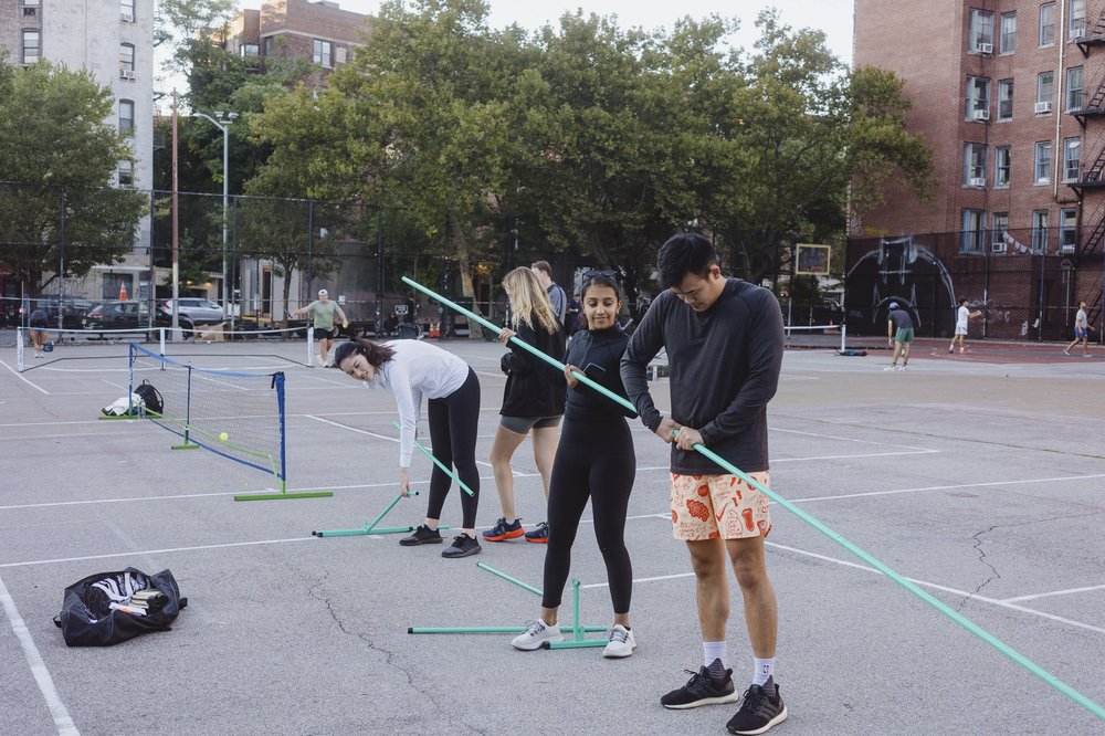 Pickleball players set up a portable net to play on the blacktop at William F. Passannante Ballfield.
