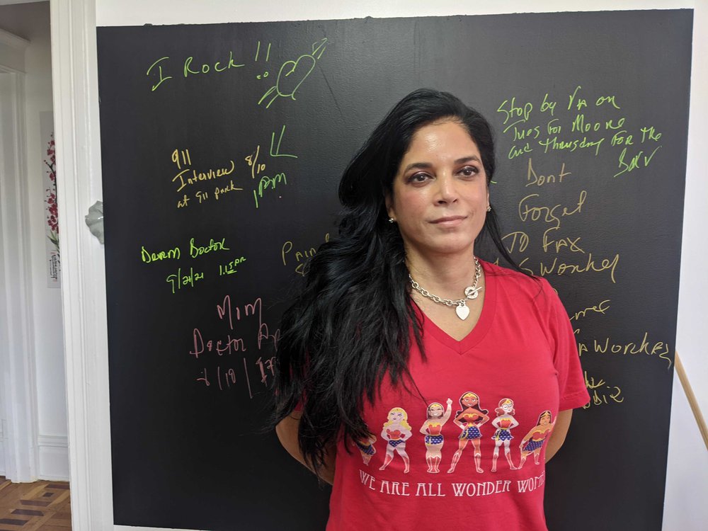 Ivonee Sanchez, in a red shirt, stands in front of a chalkboard
