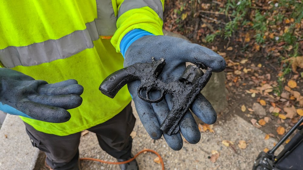 A gloved hand holds a rusty, grimy revolver.