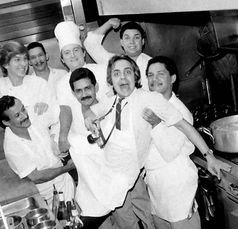 A man held aloft in a restaurant kitchen by several people
