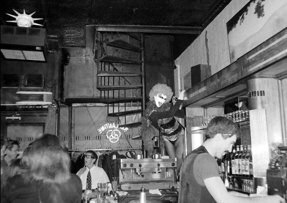 A black and white photo of the interior of a restaurant with a bar scene.