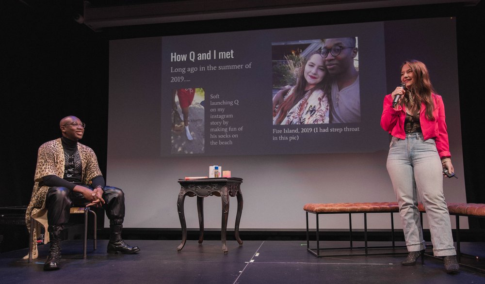 A person onstage in a red top and jeans makes a presentation.
