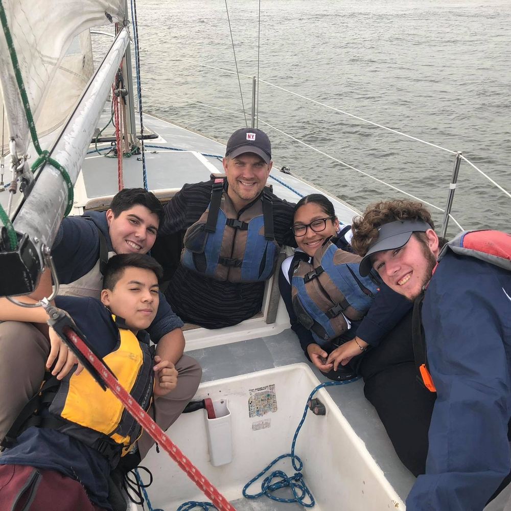 Sailing is one of the Harbor School’s competitive sports. Pictured in the center is Principal Jeff Chetirko with students on a sailboat.