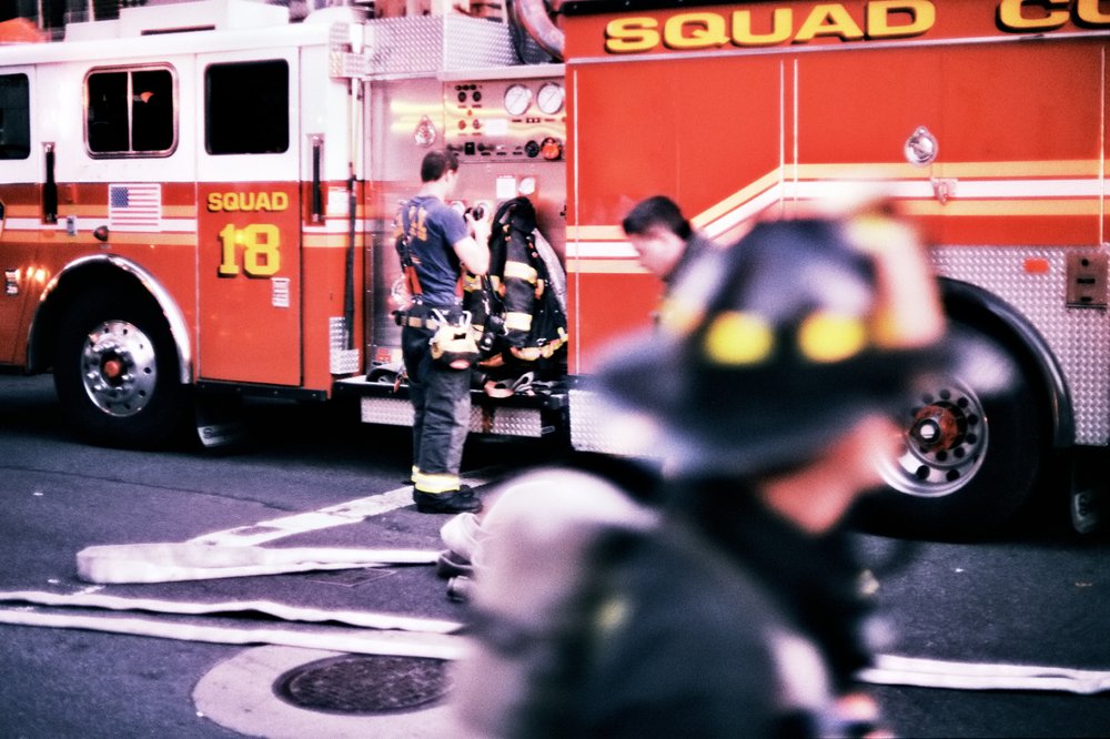 Two firefighters in front of a red FDNY fire truck.