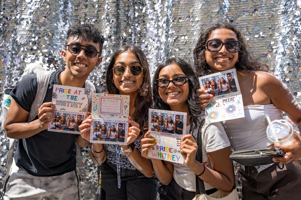 Four people hold papers and cards that say "Pride."