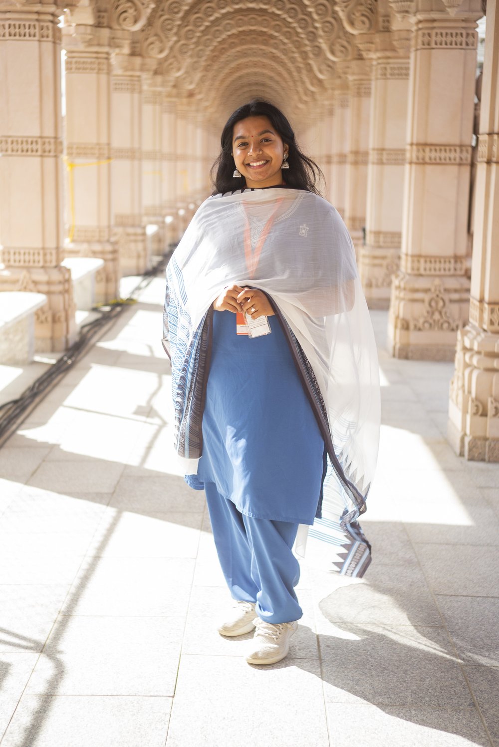 A person stands in a dramatic archway, smiling at the camera.