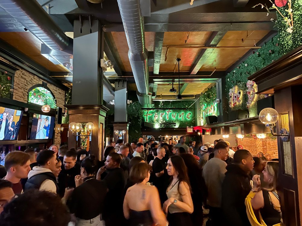 A group of people crowds into a bar.