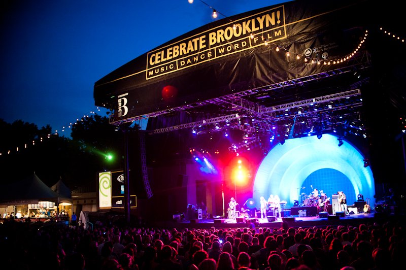 An outdoor stage at night with a sign that says "Celebrate Brooklyn"