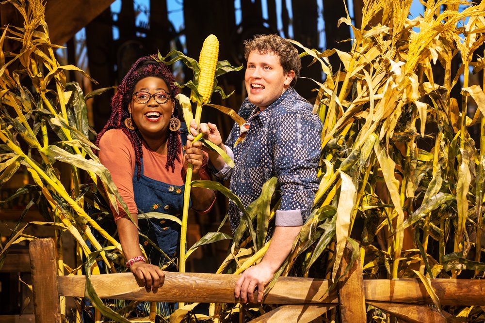 Two actors stand in a cornfield