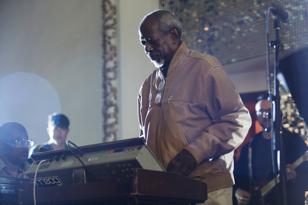 A man looking downward at a synthesizer keyboard