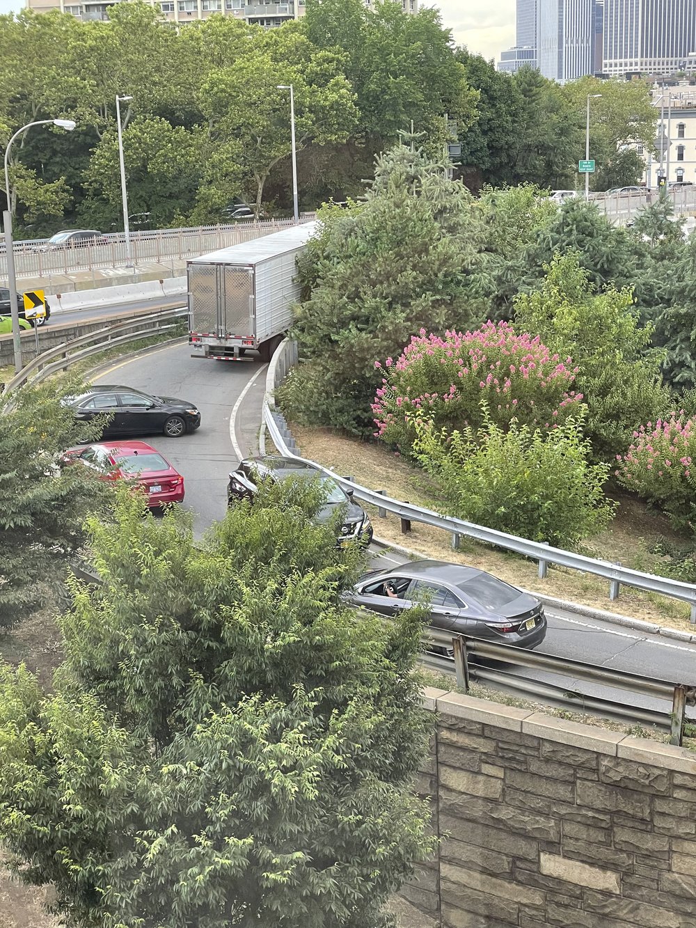 Cars and an 18-wheeler truck driving up a ramp towards a bridge