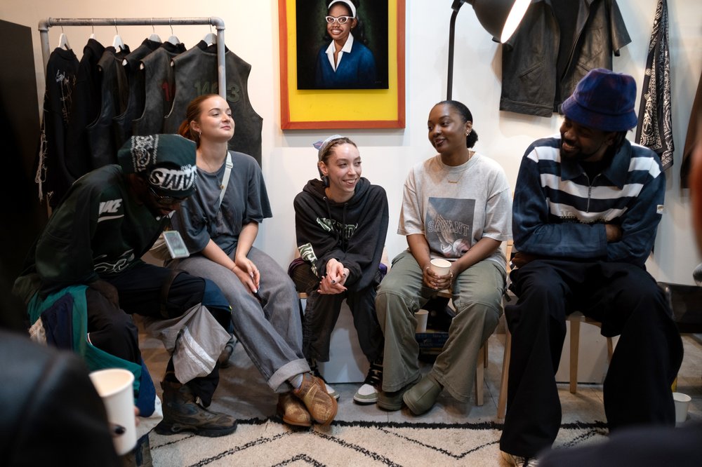 A group of people sit near each other inside a clothing store.