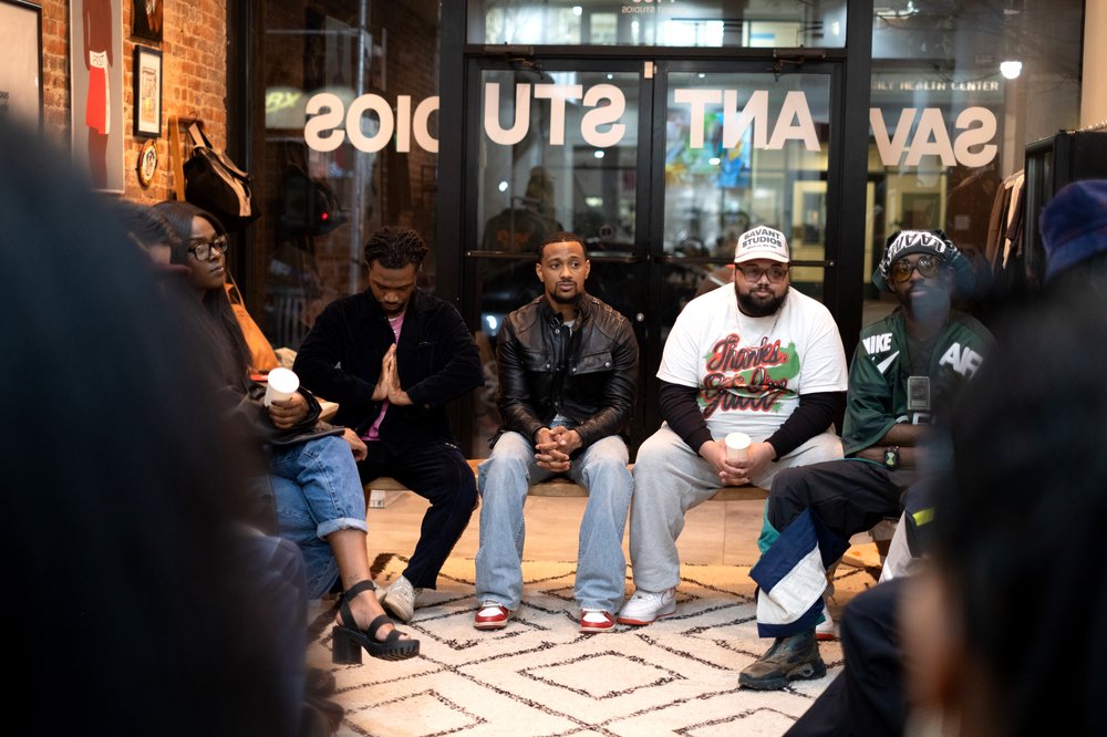 A group of people sit inside a clothing store.