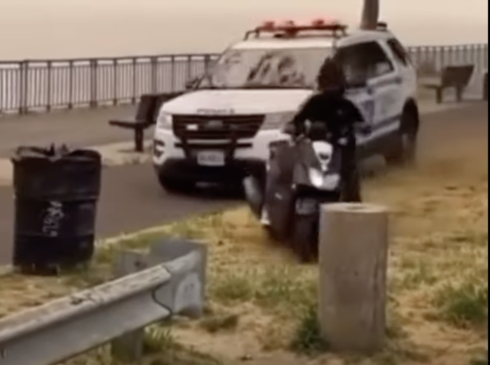 A screenshot of video capturing police chasing a moped driver