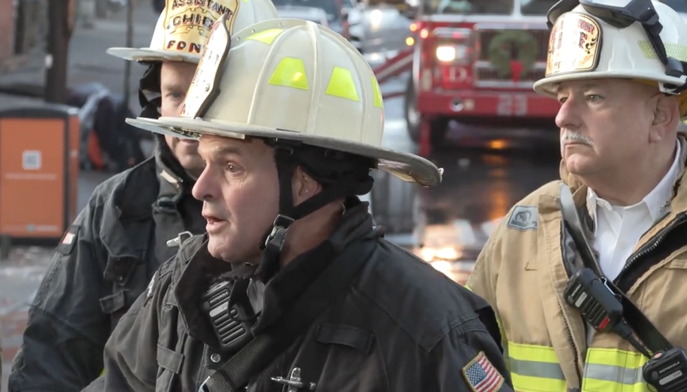 A photo of fire officials briefing reporters at the scene of a five-alarm Bronx fire.