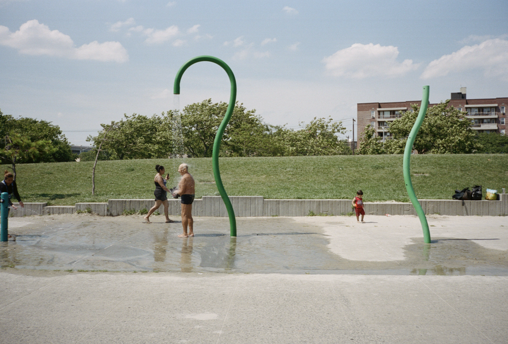 A photo of an older man showering beneath a hilarious twisty green pipe.