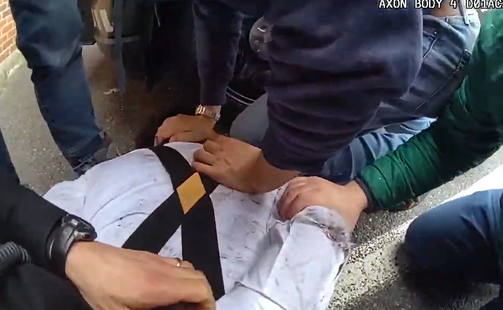 Body cam footage of a man being held down by many members of law enforcement.